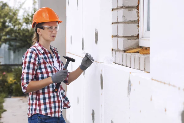 用聚泡沫把房子隔热 女工正在检查建筑水平 检查在立面安装聚苯乙烯板的准确性 — 图库照片