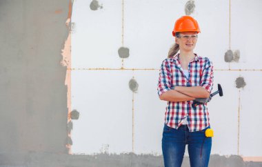 Evin poliköpükle izolasyonu. Kadın işçi, köpük plastikle izole edilmiş bir duvarın önünde duruyor.