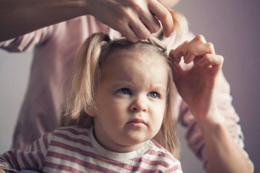 Annem küçük kızının saçını örüyor. Kapat.
