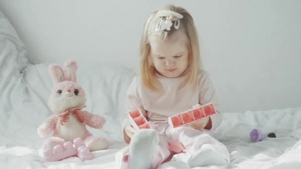 小女孩坐在床上玩着建筑商的玩具 4K视频 免版税图库视频