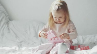 Küçük kız yatakta oturup inşaatçı oyuncağıyla oynuyor. 4k video