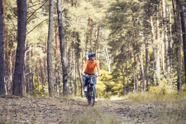 Kasklı, mutlu bir bisikletçi. Ormanda dağ bisikleti sürüyor. Macera seyahati.