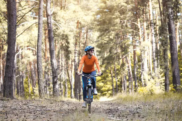 Kasklı, mutlu bir bisikletçi. Ormanda dağ bisikleti sürüyor. Macera seyahati.