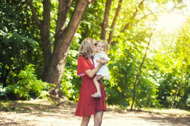 Anne ve küçük kızı parkta birlikte oynuyorlar.