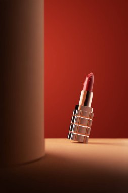 Yakın plan güzel kırmızı ruj. Turuncu arka planda su damlaları var.