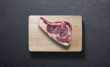 Düz bir zeminde biftek ve yukarıdan kesilmiş bir tahta.