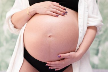 Stüdyoda ilk çocuğunu kutlayan hamile bir kadın.