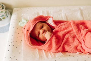 İlk banyosundan sonra havlunun üstünde iki haftalık bir bebek.