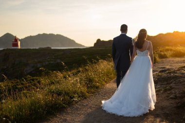 Gelin ve damat düğünden sonra deniz fenerine doğru yürüyorlar.