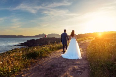 Gelin ve damat düğünden sonra deniz fenerine doğru yürüyorlar.