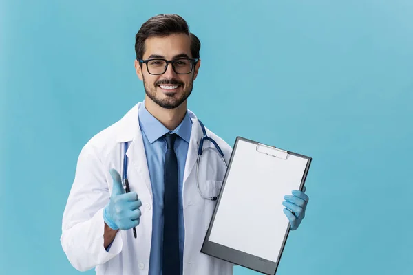 Male doctor in a white coat and glasses with a medical record and a stethoscope smile on a blue isolated background, copy space, space for text. High quality photo