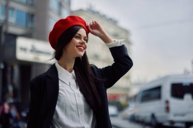 İş dişleri olan gülümseyen bir kadın şehirde ofis binalarının arka planında, şık kıyafetler ve makyaj malzemeleriyle, bahar yürüyüşü, seyahat. Yüksek kalite fotoğraf