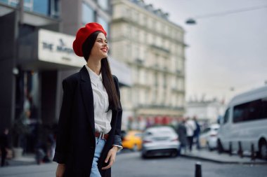 İş dişleri olan gülümseyen bir kadın şehirde ofis binalarının arka planında, şık kıyafetler ve makyaj malzemeleriyle, bahar yürüyüşü, seyahat. Yüksek kalite fotoğraf