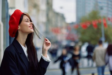 Güzel, gülümseyen, dişleri olan bir kadın şehirde ofis binalarının arka planında yürüyor şık, modaya uygun eski moda kıyafetler ve makyaj malzemeleri, sonbahar yürüyüşü, seyahat. Yüksek kalite fotoğraf