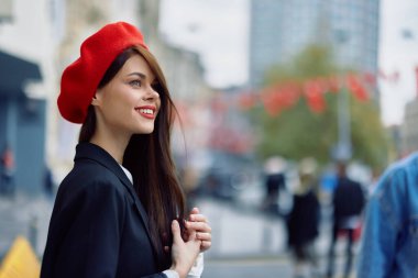 Güzel, gülümseyen, dişleri olan bir kadın şehirde ofis binalarının arka planında yürüyor şık, modaya uygun eski moda kıyafetler ve makyaj malzemeleri, sonbahar yürüyüşü, seyahat. Yüksek kalite fotoğraf