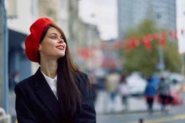 Güzel, gülümseyen, dişleri olan bir kadın şehirde ofis binalarının arka planında yürüyor şık, modaya uygun eski moda kıyafetler ve makyaj malzemeleri, sonbahar yürüyüşü, seyahat. Yüksek kalite fotoğraf