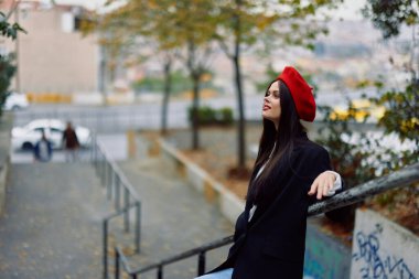 Moda kadını şehir zemininde kırmızı dudaklı, kırmızı bereli, gezgin, sinematik renk, eski moda tarzı, şehir modası tarzıyla yürüyor. Yüksek kalite fotoğraf