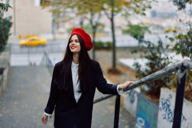 Moda kadını şehir zemininde kırmızı dudaklı, kırmızı bereli, gezgin, sinematik renk, eski moda tarzı, şehir modası tarzıyla yürüyor. Yüksek kalite fotoğraf