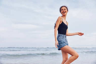 Kadın plaj yaşam tarzı, gün doğumunda koşan biri okyanusta güneşlenir, güneşlenir, gülümser, yaz mevsimi, seksi gülümsemeler, güzel.