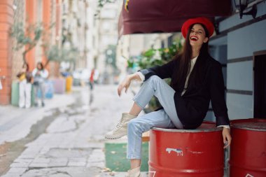 Dişleriyle gülümseyen güzel bir kadın, şehir caddesindeki bir kafenin önünde, şık bir moda elbisesi, tatili ve seyahati var. Yüksek kalite fotoğraf