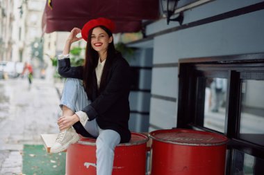 Neşeli bir kadın, dişleriyle bir kafe ve barın önünde oturmuş gülümsüyor, şık giyiniyor, tatil yapıyor ve seyahat ediyor. Yüksek kalite fotoğraf