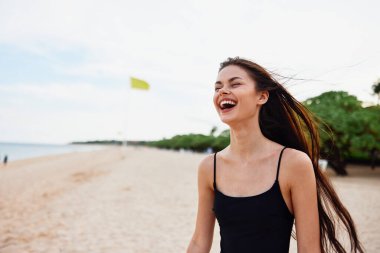 Kadın gün batımında özgürce yürüyor okyanus yaz kumsalı gülümse tropikal kum kız rahat giyin denizin tadını çıkar uzun gökyüzü tatilinin tadını çıkar genç yetişkin