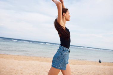 Eğlenceli bir kadın, deniz kenarında yürüyor, gülümsüyor, güneş batıyor, kadın, hayat tarzı, yaz mevsiminde plajda koşuyor, uçuyor, gülümseyen okyanus bikinisi.