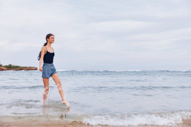 Günbatımında koşan kadın gülümseyerek mutlu kumsal aktiviteleri mutlu yaz dalgaları genç gülüşler doğa uçuşları bikinili deniz yolculukları
