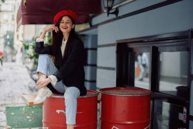 Güzel bir kadın, dişleriyle bir kafe ve barın önünde oturmuş gülümsüyor. Şık bir elbise, tatil ve seyahat. Yüksek kalite fotoğraf