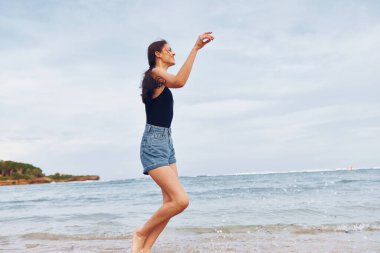 Plajda koşuşturan pozitif gülüşlü seksi genç seyahat eden deniz uçuşu yaşam tarzı fotokopi çeken gün batımı okyanusu.