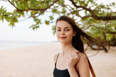 Çantalı kadın okyanus doğası insanı güler tropikal ücretsiz tatil gülümser yürüyen genç kumsal bayramı yetişkin yaz tatili elbisesi kum deniz güneşi
