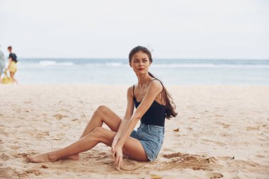 Kadın doğal yaşam tarzı bronz beyaz su okyanusta oturuyor güzel deniz manzarası kumsal gezisi gülüşü ve özgürlük saçı tropik çekicilik