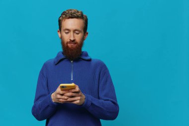 Elinde telefonla konuşan, arayan, mavi bir arka planda olan bir adamın portresi. Çevrimiçi sosyal medya iletişimi, yaşam tarzı. Yüksek kalite fotoğraf