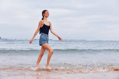 Deniz kılı çalıştıran, yürüyen, günbatımı, sahil seyahati, kumsal, yaz bikini, genç gülümseme, kadın mutluluğu dalgaları.