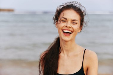 Gün batımı kadını gülümsüyor. Güzellik, gençlik, huzur dolu özgürlük. Mutlu kıyı, okyanus, kadın, yaz, sahil, tatil, deniz manzarası.