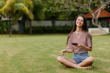 Kadın öğrenci kız öğrenci tarzı palmiye gömleği sağlıklı uygulama gülümseyen telefon tişörtü uygulaması çimen pantolonu mutlu yaz blogger park kişisi