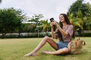 Kadın telefon akıllı bahar blogcusu cep telefonu park çalışanı ağaç başvuru öğrencisi çimen gülümsüyor çalışan şebeke mutlu kadın Palm Doğa tişörtü
