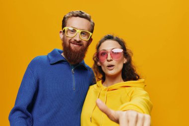 Kadın ve erkek, neşeli bir şekilde gülümsüyor, gözlükleriyle, sarı arka planda, semboller ve el hareketleri, aile fotoğrafları, yeni evliler. Yüksek kalite fotoğraf