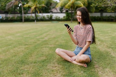 Poşet kadın blogger çim çalışan doğa avucu gülen kişi cep telefonu parkı akıllı uygulama sağlıklı yürüyüş kadın ağaç yaşam tarzı telefon konuşma