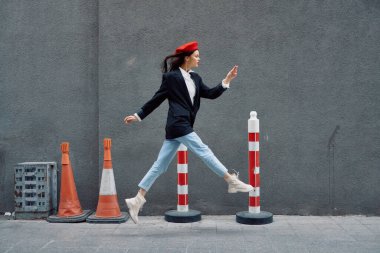Kırmızı dudaklı, kırmızı bereli, seyahatçi, sinematik renkli, modaya uygun, işe geç kalmış, koşan şehir turistinin önünde koşuşturan modacı kadın. Yüksek kalite fotoğraf