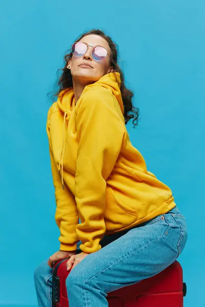 Glimlach Vrouw Zittend Een Koffer Een Gele Hoodie Blauwe Jeans — Stockfoto