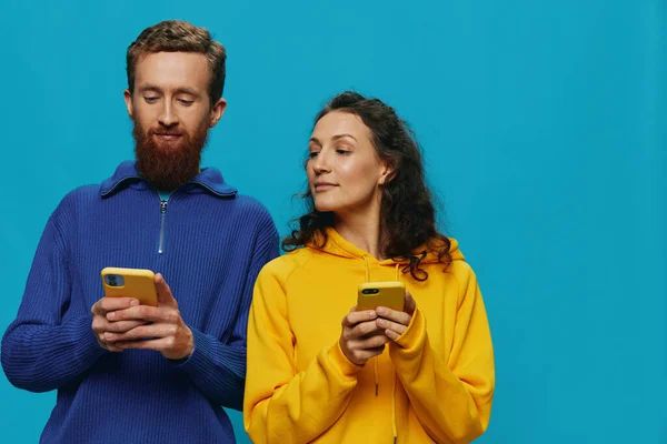 女人和男人快乐地结合在一起 手里拿着手机 弯下腰笑着 蓝蓝的背景 真正的家庭关系的概念 在电话里交谈 在网上工作 高质量的照片 — 图库照片