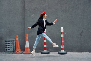 Kırmızı dudaklı, kırmızı bereli, seyahatçi, sinematik renkli, modaya uygun, işe geç kalmış, koşan şehir turistinin önünde koşuşturan modacı kadın. Yüksek kalite fotoğraf