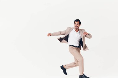 Arka planda duran, iş adamı modelliği yapan, kendine güvenen, sakallı, gülümseyen bej takım elbiseli, çekici, iş adamı, mutlu, gülümseyen, zafer beyaz bir adam.