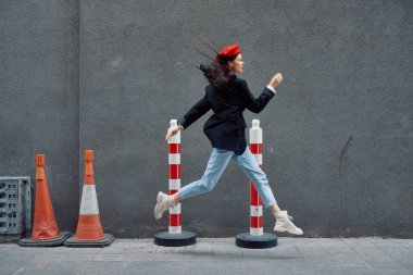 Kırmızı dudaklı, kırmızı bereli, seyahatçi, sinematik renkli, modaya uygun, işe geç kalmış, koşan şehir turistinin önünde koşuşturan modacı kadın. Yüksek kalite fotoğraf