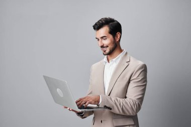 Girişimci bilgisayar, neşeli takım elbiseli yakışıklı. İnternette dizüstü bilgisayarı yazan, yetişkin, kopyalama işi yapan serbest çalışan, mutlu, genç, gülümseyen bir internet işçisi.