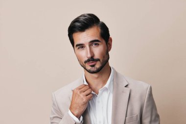 Ofisteki işadamı genç işadamının gülümsemesini engelledi. Başarılı bir şekilde bej renkli bir iş adamı gibi poz verdi. Resmi kravat yakışıklı, katlanmış takım elbise.