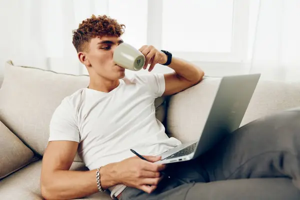男人内部技术坐在家里打电话给人生活方式现代高加索式笔记本电脑T恤衫房间浏览看打字男性笔记本电脑 — 图库照片