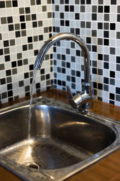 Clean sink with pouring water in the kitchen, metal faucet and sink in an old home interior. High quality photo