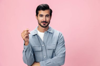 Sakallı şık esmer adam pembe bir arka planda beyaz tişört ve kot pantolonla kameraya bakıyor ve yüzünde neşeli bir gülümseme, kopyalama alanı. Yüksek kalite fotoğraf